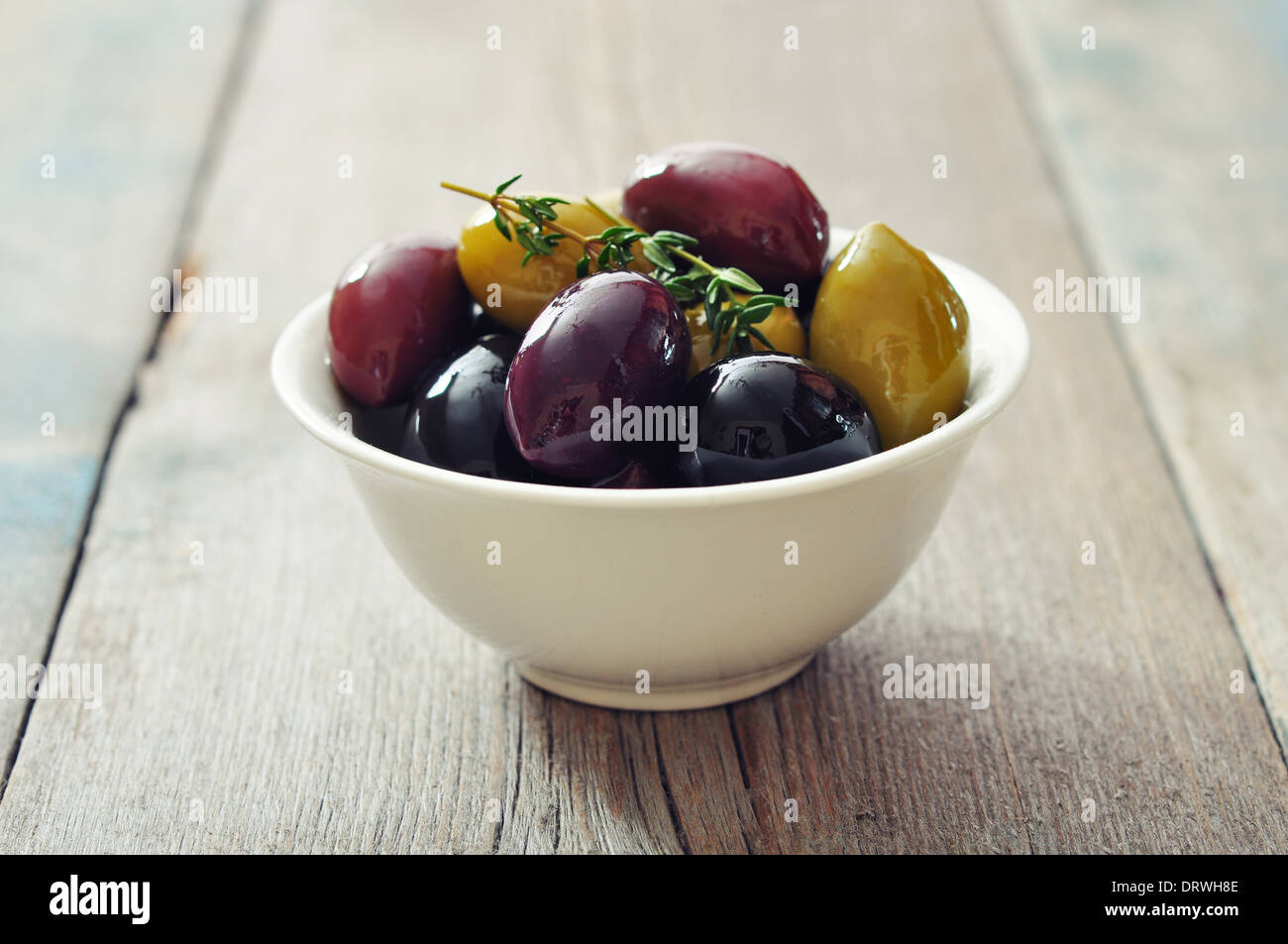 Different kinds of olives in bowl on wooden background Stock Photo