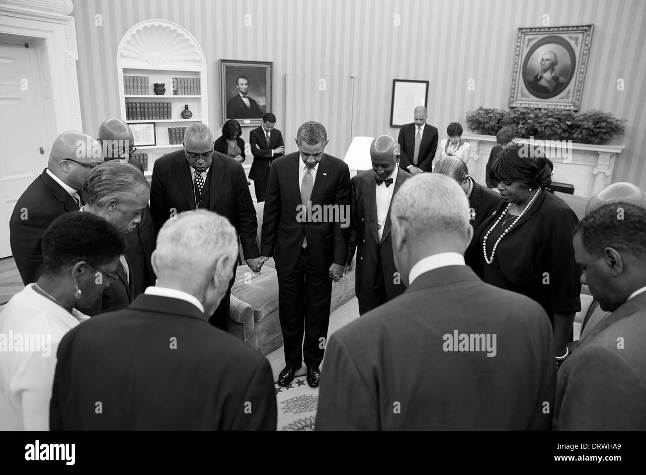 US President Barack Obama prays with faith leaders in the Oval Office of the White House following a meeting to discuss the 50th anniversary of the March on Washington for Jobs and Freedom August 26, 2013 in Washington, DC. Stock Photo