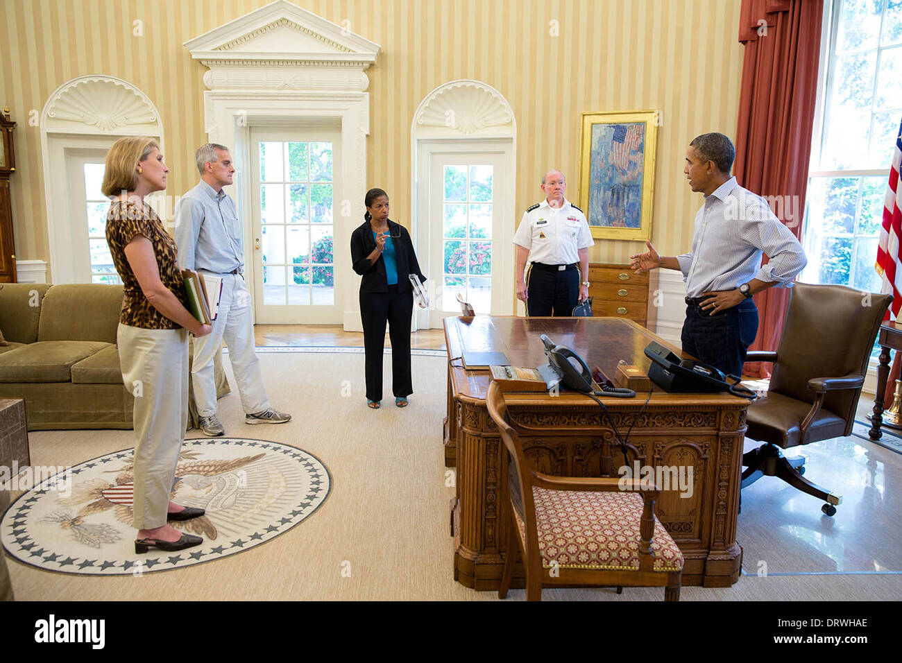 US President Barack Obama discusses the situation in Syria with senior advisors in the Oval Office of the White House August 24, 2013 in Washington, DC. Standing from left are: Karen Donfried, Senior Director for European Affairs; Chief of Staff Denis McDonough; National Security Advisor Susan E. Rice; and Gen. Martin Dempsey, Chairman of the Joints Chiefs of Staff. Stock Photo
