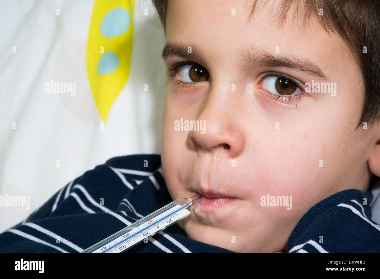 Sick child in bed. Measuring the temperature with a thermometer Stock