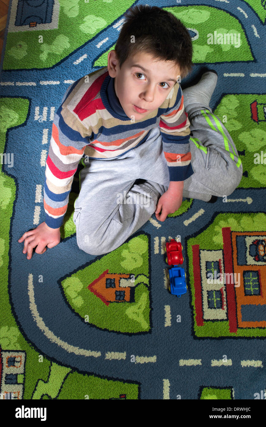 Child is playing with cars on carpet. Stock Photo