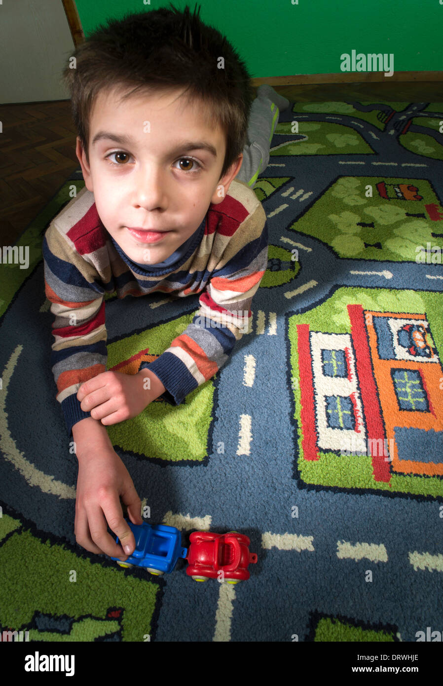 Child is playing with cars on carpet. Stock Photo