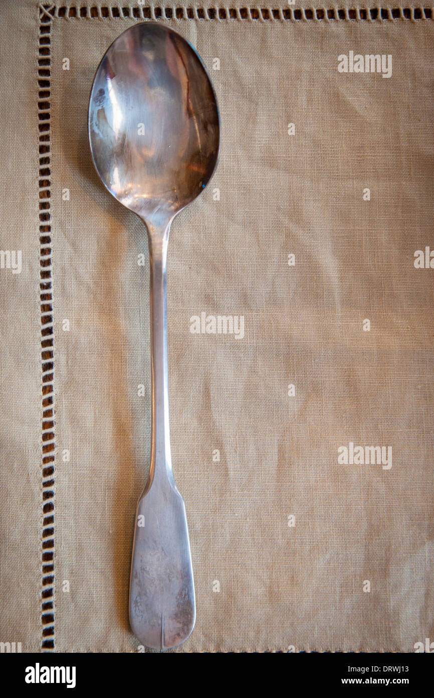 Old silver serving spoon on linen tablecloth Stock Photo