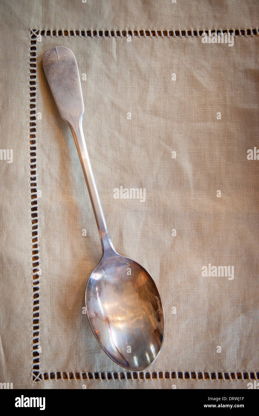 Old silver serving spoon on linen tablecloth Stock Photo