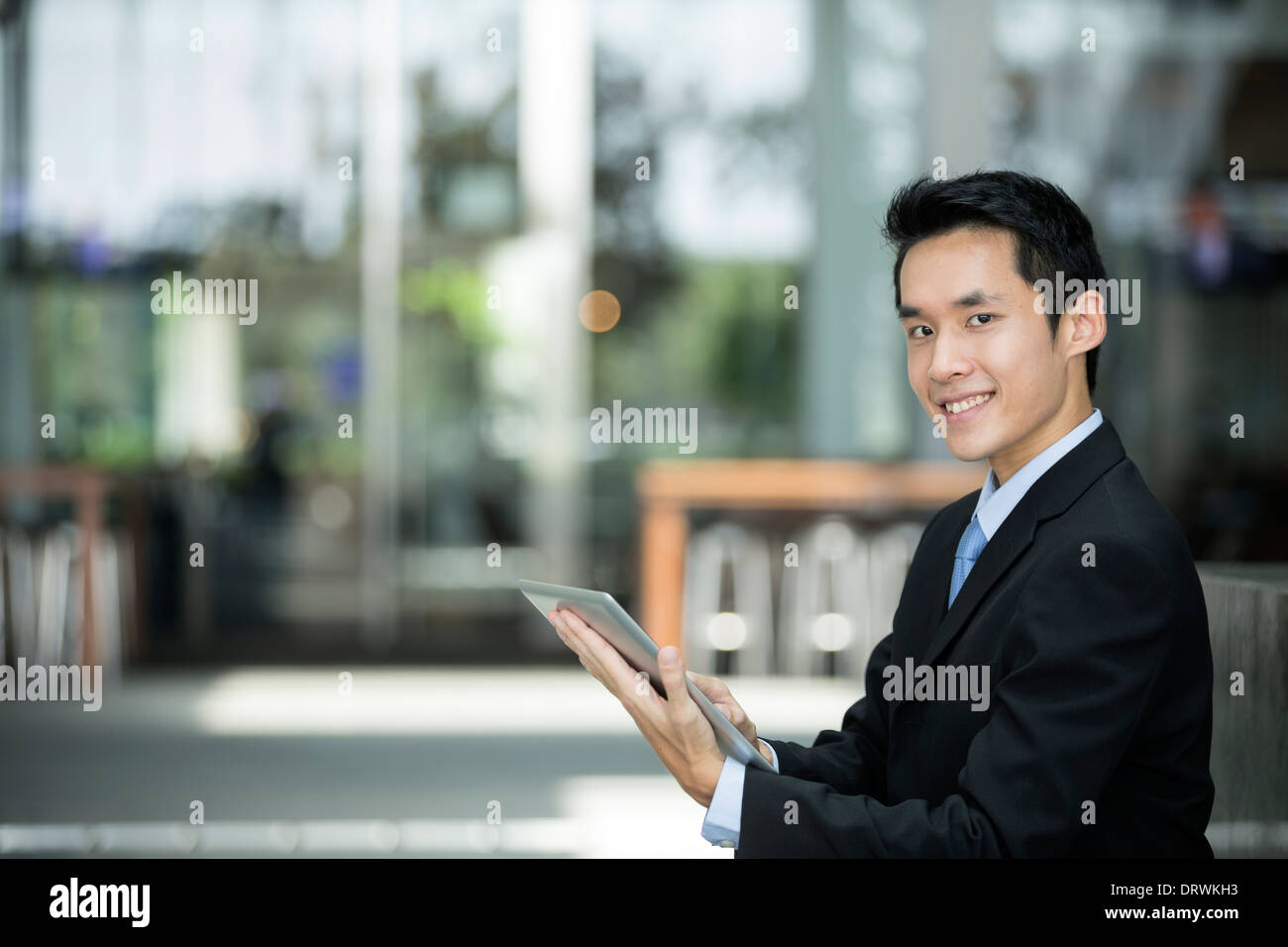 Chinese man with a tablet computer. Asian business man using digital tablet computer outside. Stock Photo