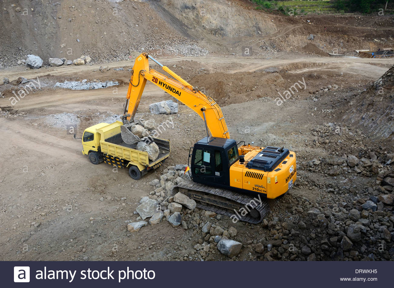 A new Hyundai 210LC-7H excavator loads large rocks into dump truck on  construction site