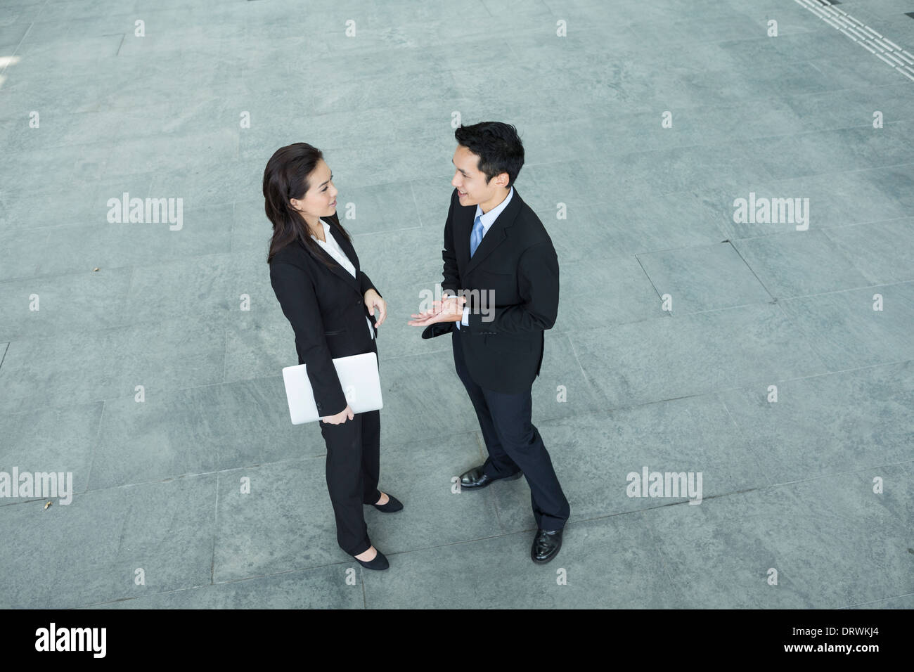 Above view of two Happy Chinese Business colleagues standing outside office & talking to each other. Stock Photo