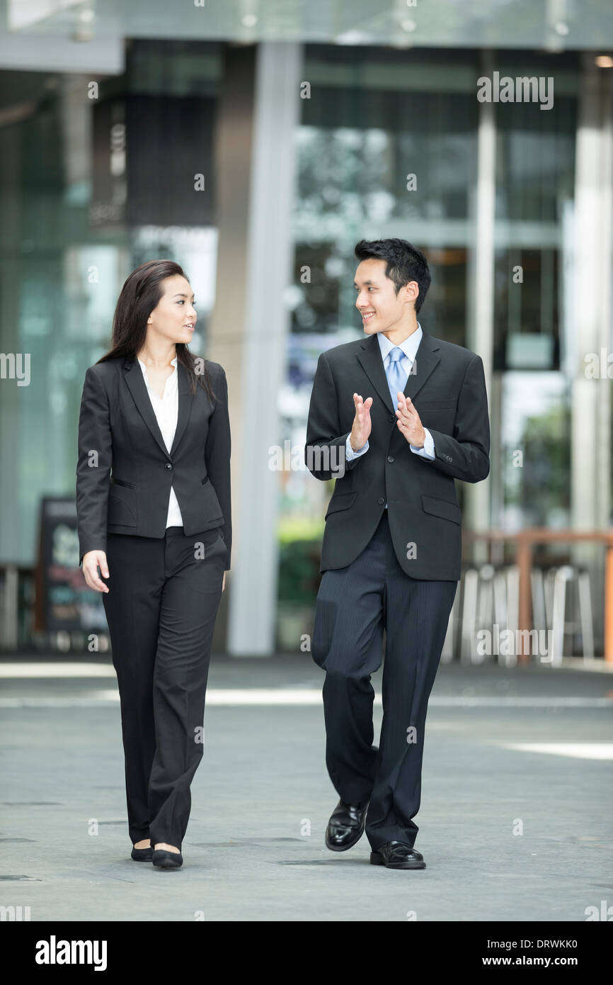 Happy Chinese Business colleagues walking outside office & talking to each other. Stock Photo