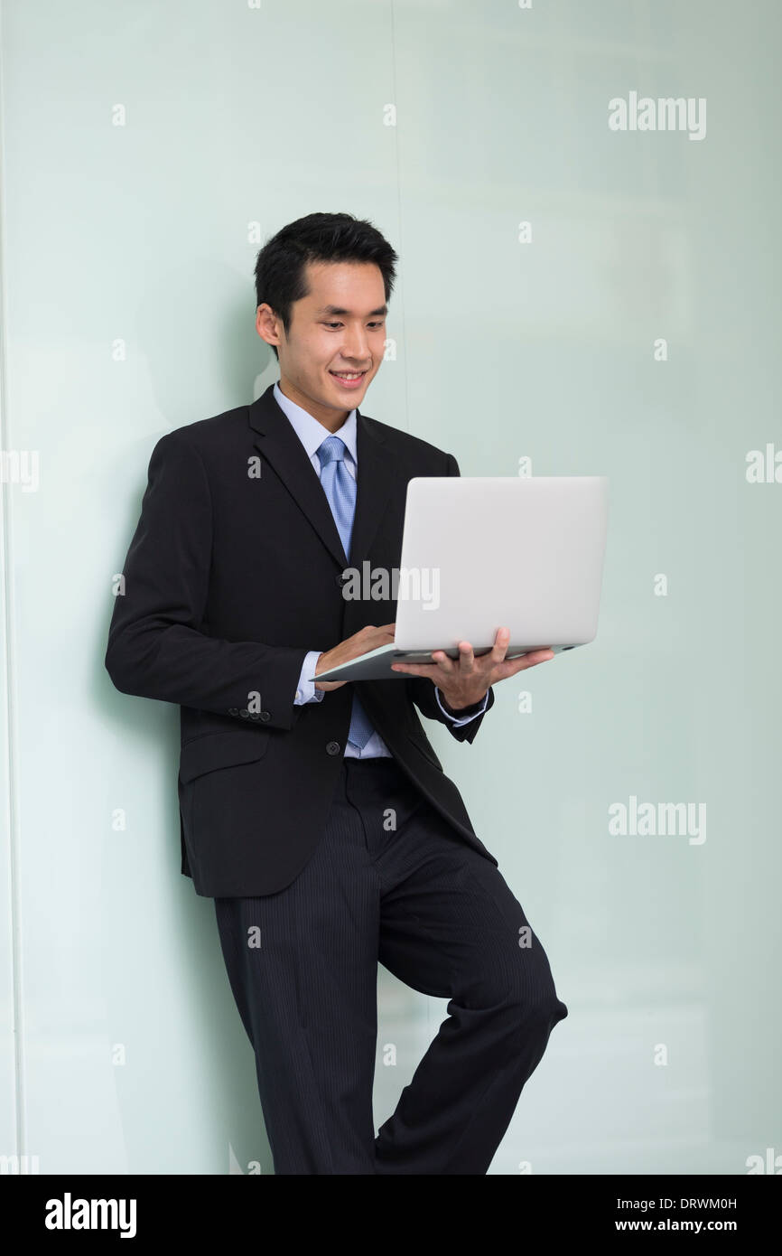 Chinese business Man using his laptop out doors in modern city. Business on the go concept. Stock Photo