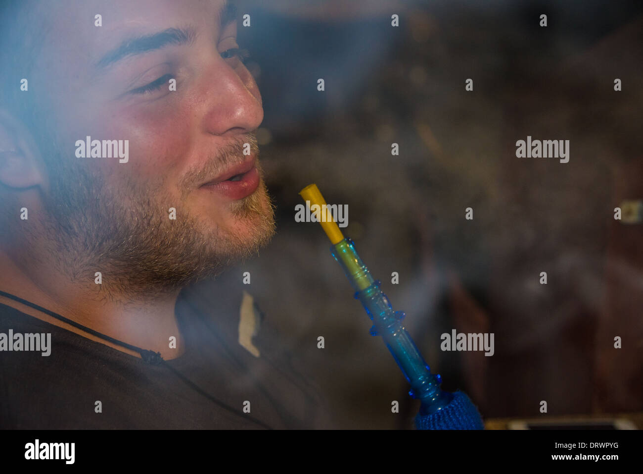smoking a shiska young man smokes a waterpipe on a hot evening at a lebonese restaraunt, happy smiling Stock Photo