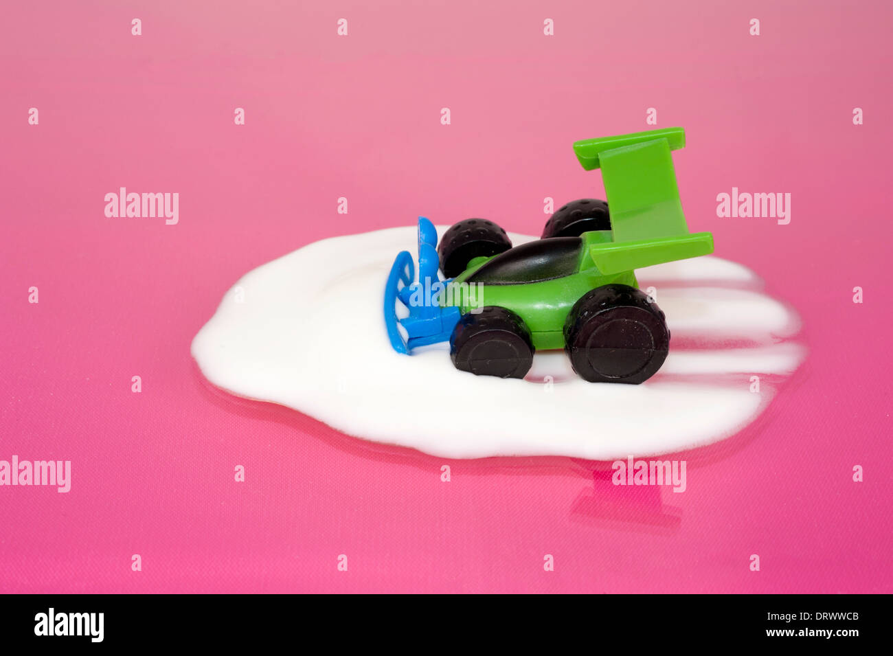 Toy car driving into pool of yogurt on a pink surface Stock Photo
