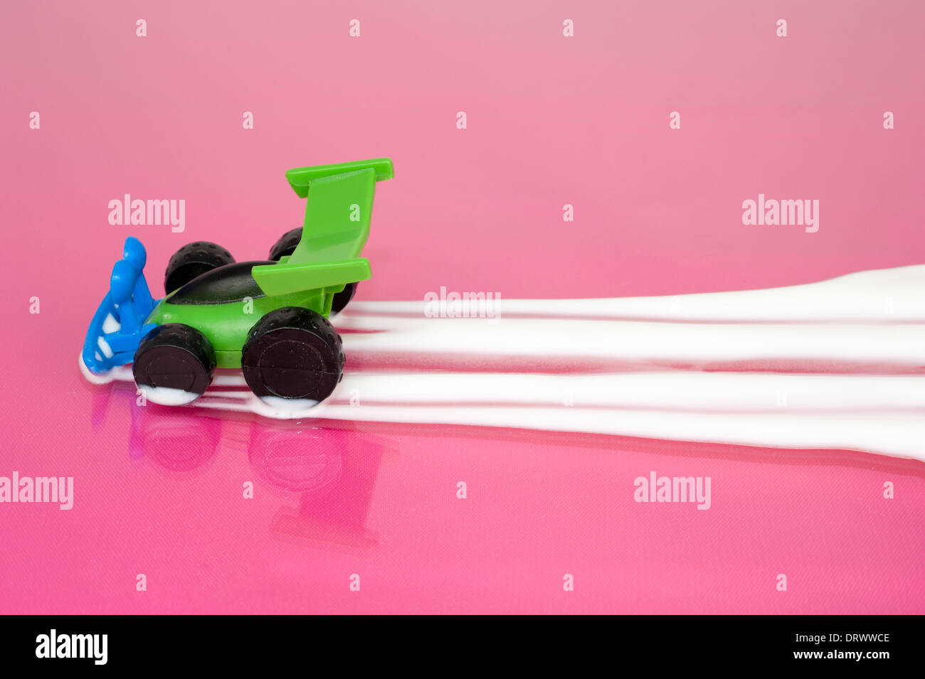 Toy car leaving a trail of yogurt on a pink surface Stock Photo