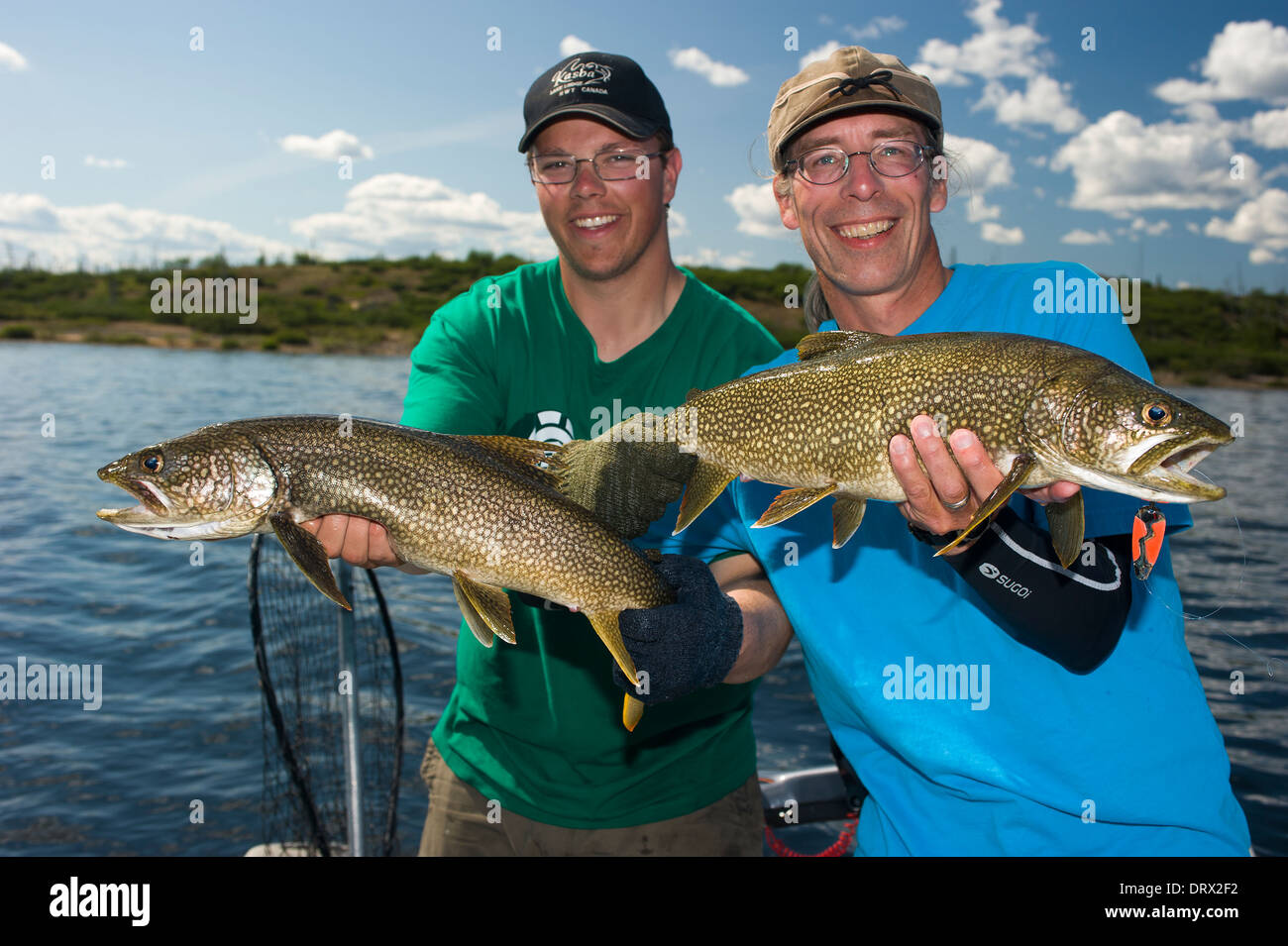 Fishing buddies hold up their summer lake trout catch in a boat on a lake in Northern Ontario. Stock Photo