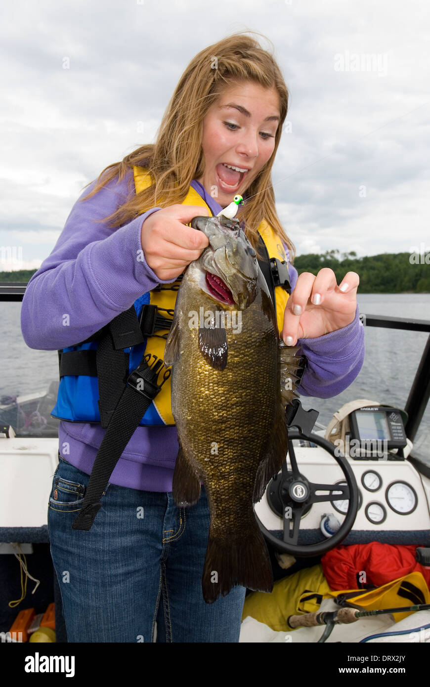 Surprised young woman angler holding up the smallmouth bass she caught in a  boat in a lake in Northern Ontario Stock Photo - Alamy