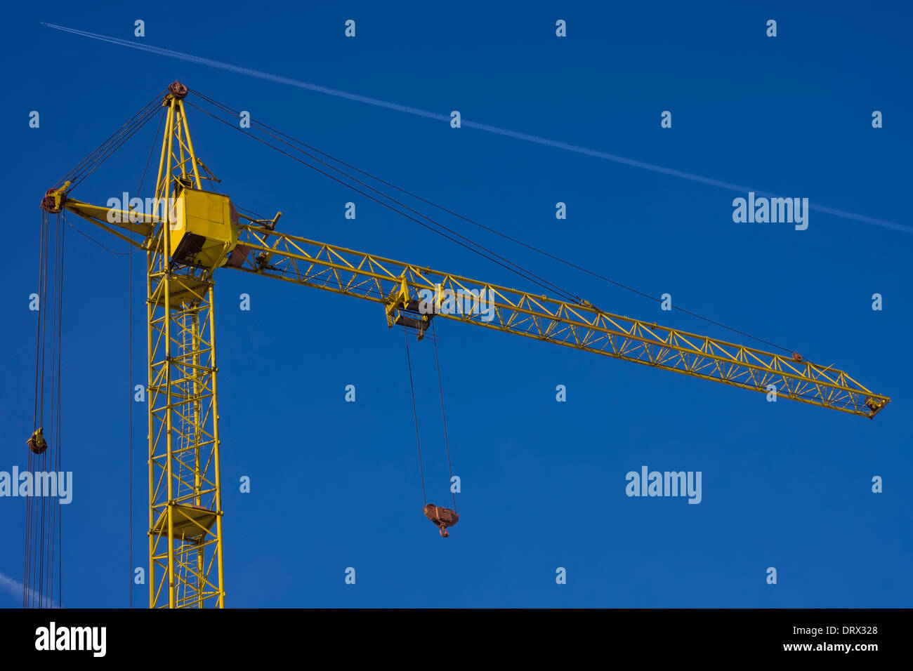 Top of tower crane against blue sky background with jet trace Stock Photo