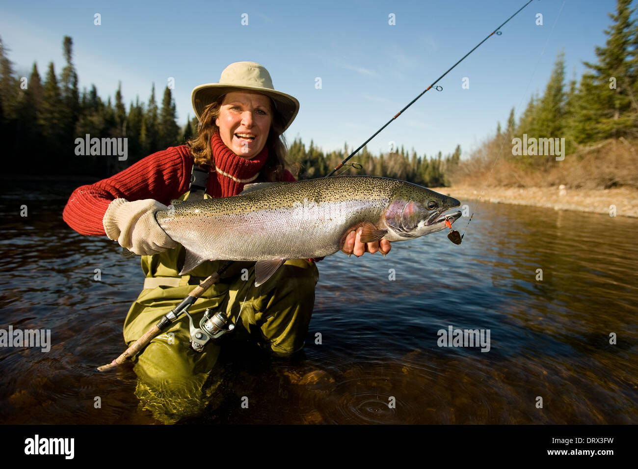 Woman angler holding a large steelhead caught in a river in Northern Ontario, Canada Stock Photo