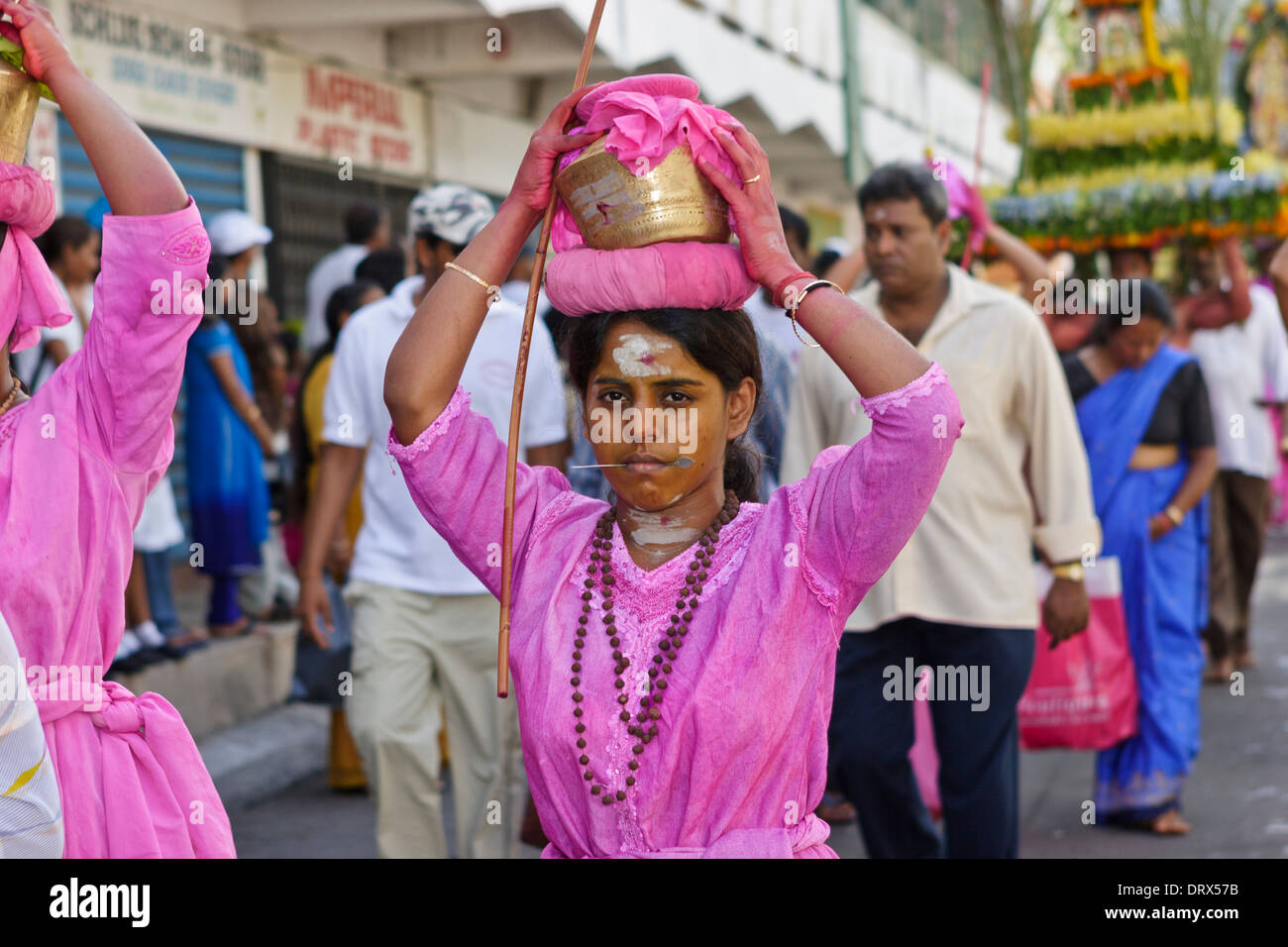 A women devotee carrying a pot of sacred milk and cheeks pierced with a silver spear during the Thaipoosam Cavadee festival. Stock Photo