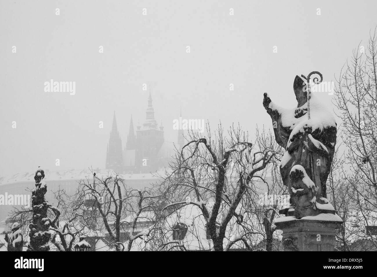 Black and white image of snow covered saint on the Charles Bridge in Prague, Czech Republic. Stock Photo