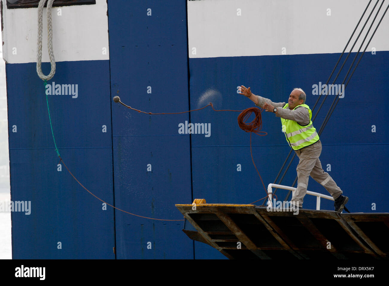 Ship crew guiding heavy duty mooring rope during docking procedure ...