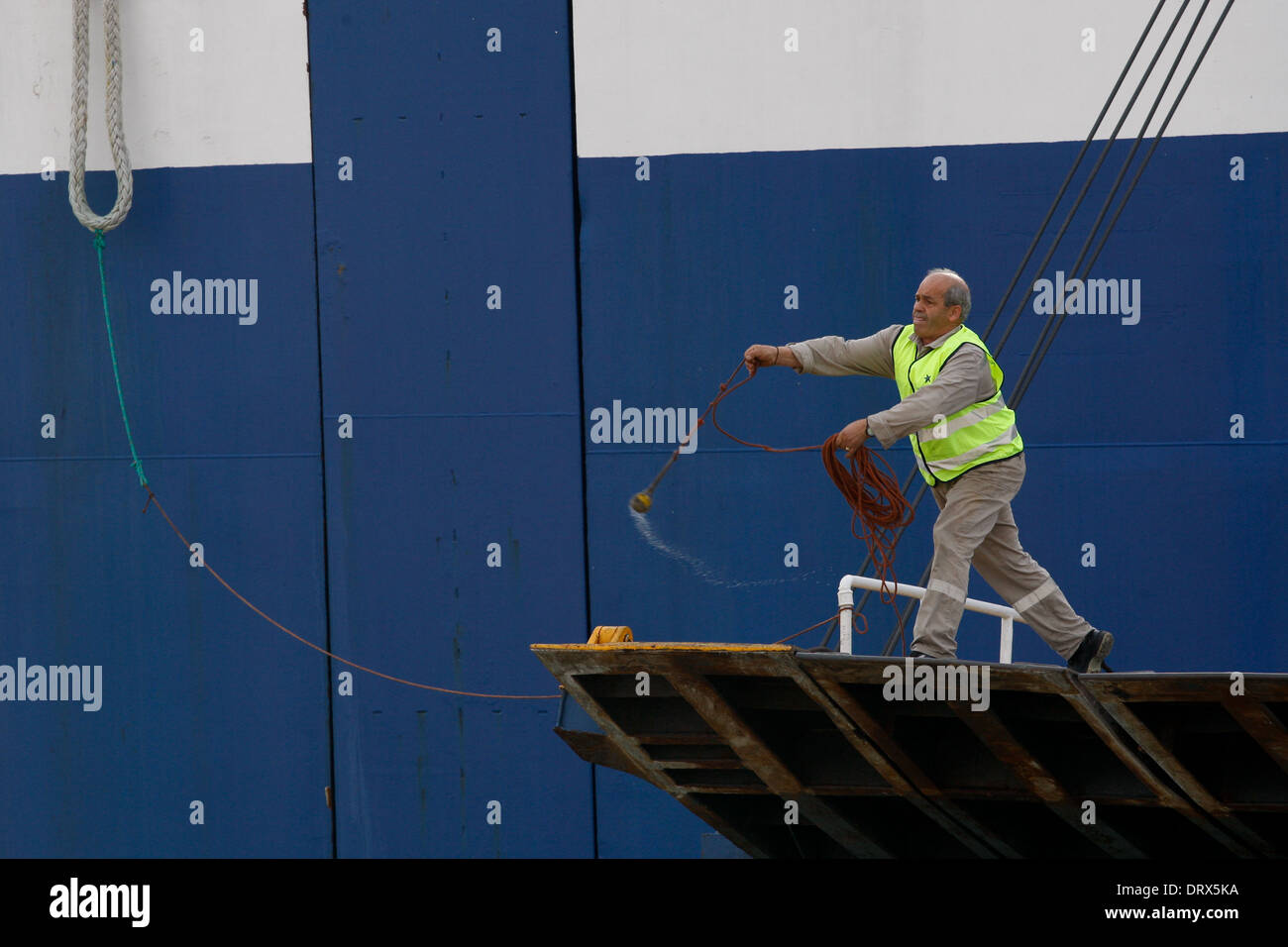 Ship crew guiding heavy duty mooring rope during docking procedure ...