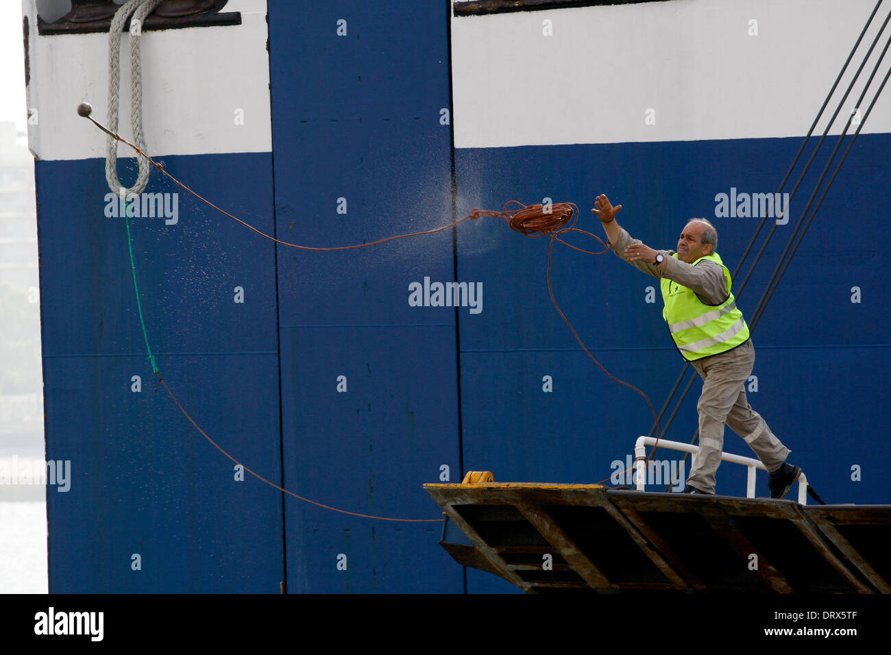 Ship crew guiding heavy duty mooring rope during docking procedure ...