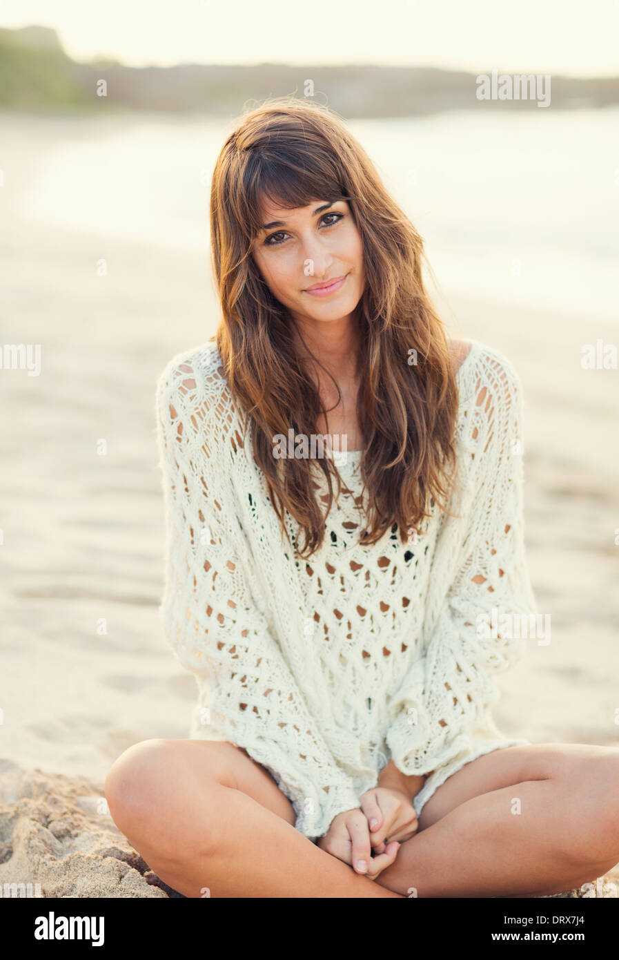 Beautiful young woman in sweater on the beach at sunset, Fashion lifestyle warm backlit sunlight Stock Photo