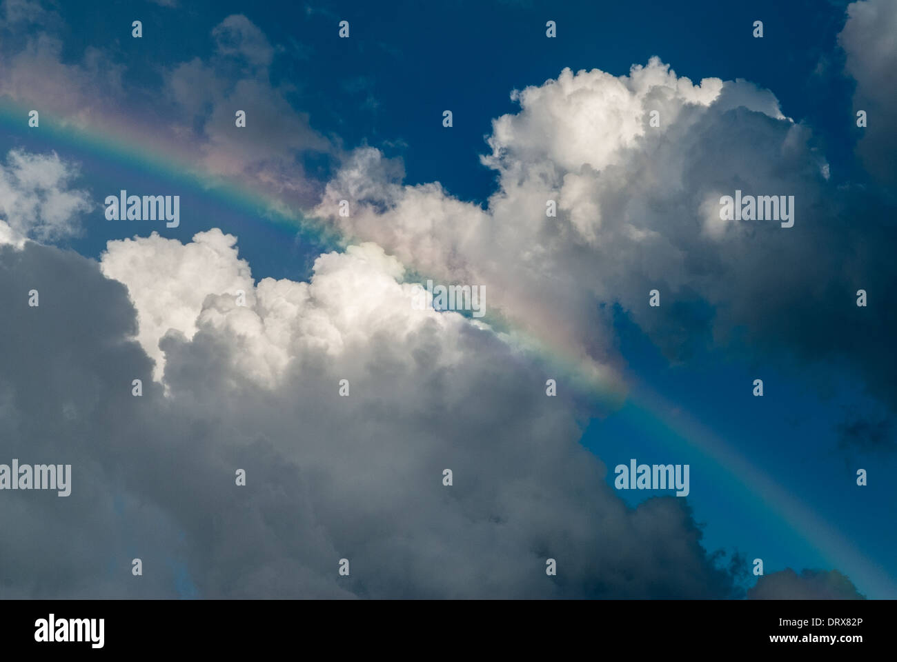 Rainbow on blue sky with white clouds Stock Photo