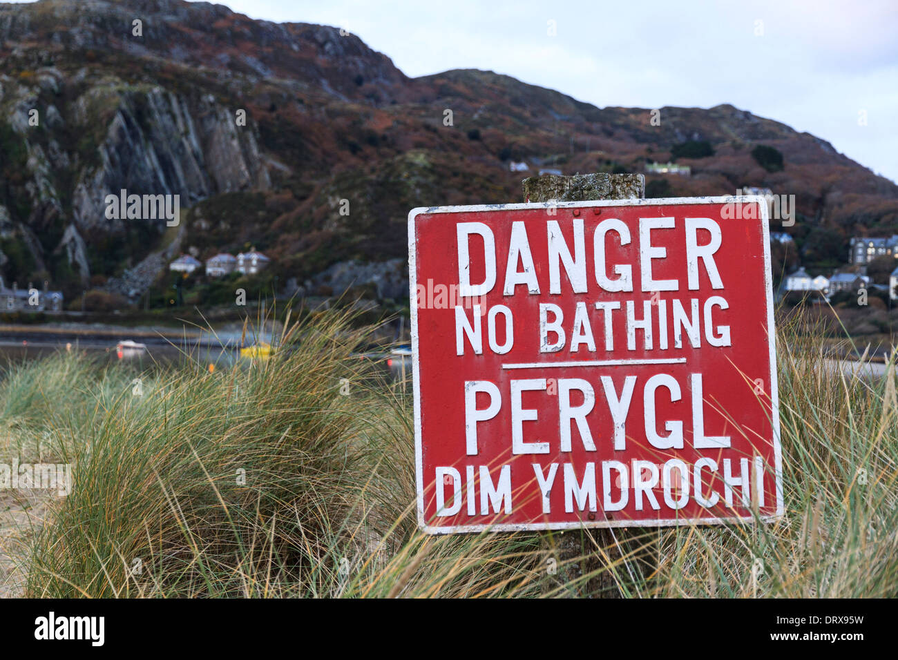 A red warning sign reads 'Danger No Bathing' and in Welsh 'Perygl Dim Ymdrochi' at Fairbourne on the mid Wales coast Stock Photo