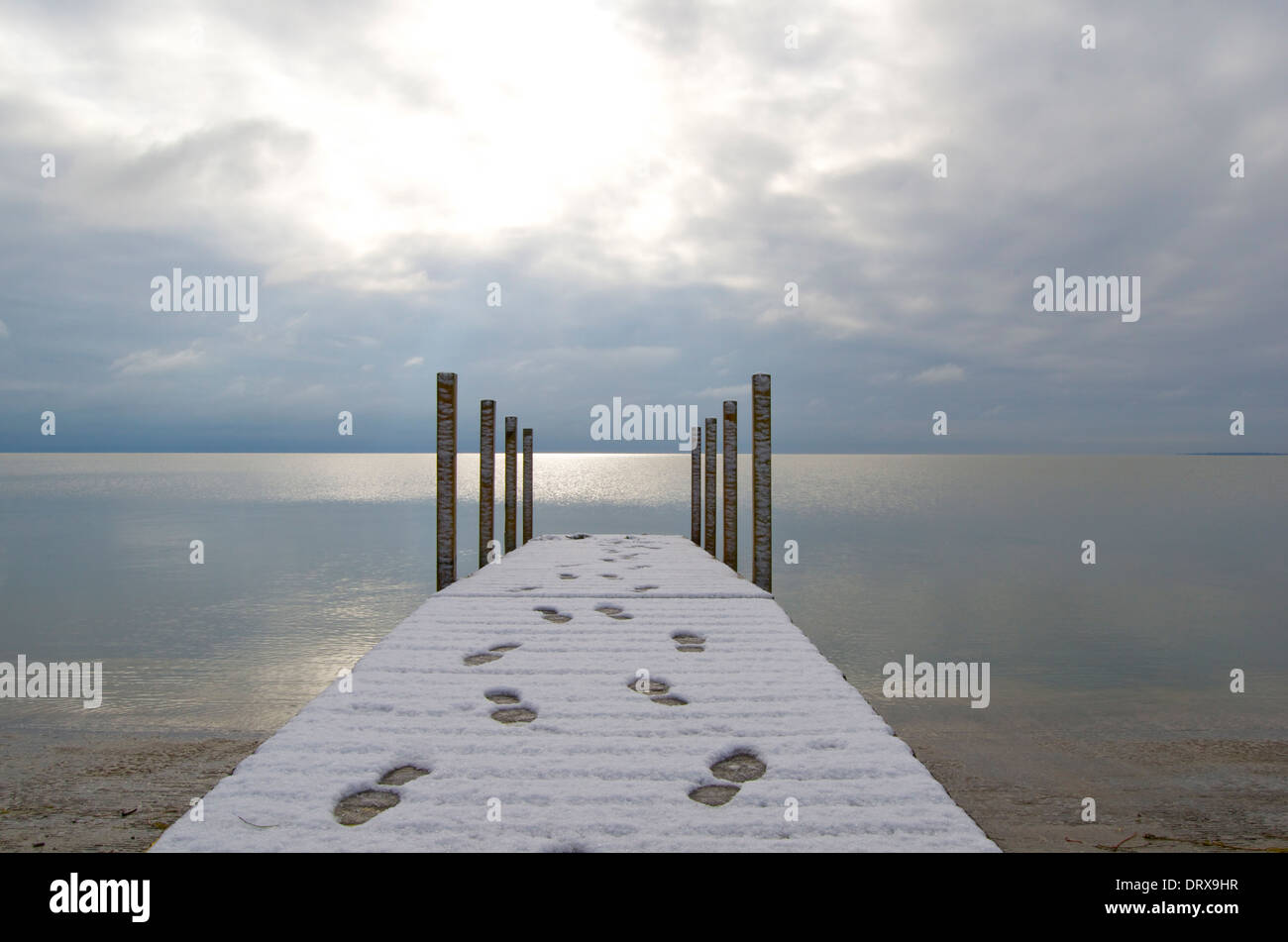 Dock with snowy surface and human footprints leading out and back Stock Photo