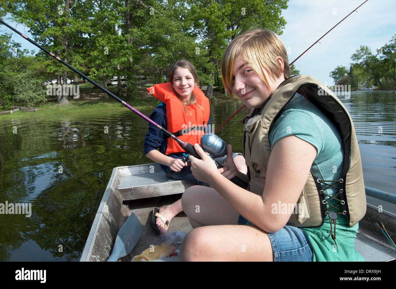 Two girls fishing on a boat wearing life jackets Stock Photo