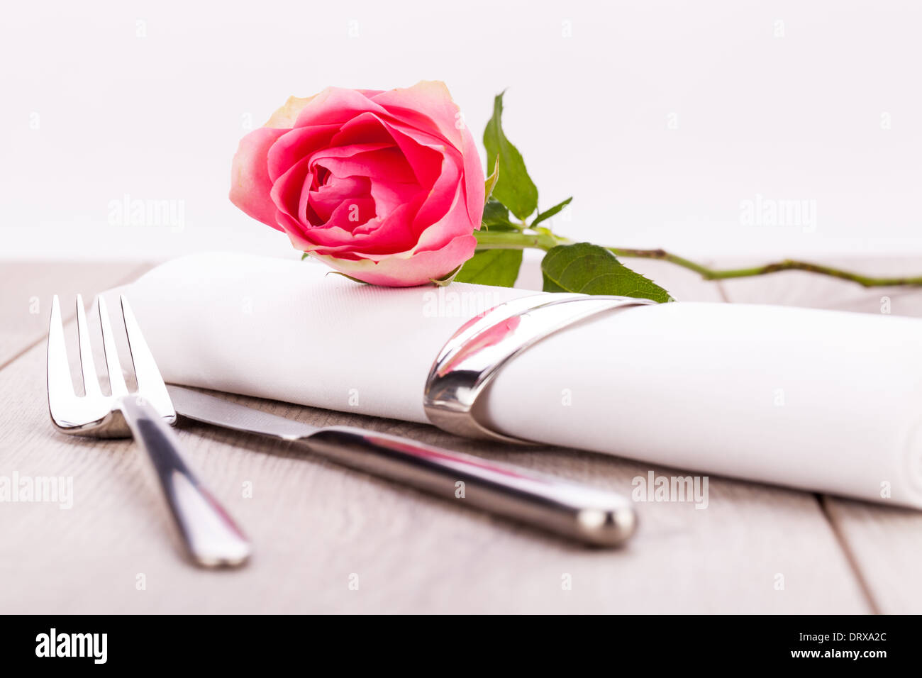 Romantic formal elegant table setting with a single pink rose and ...