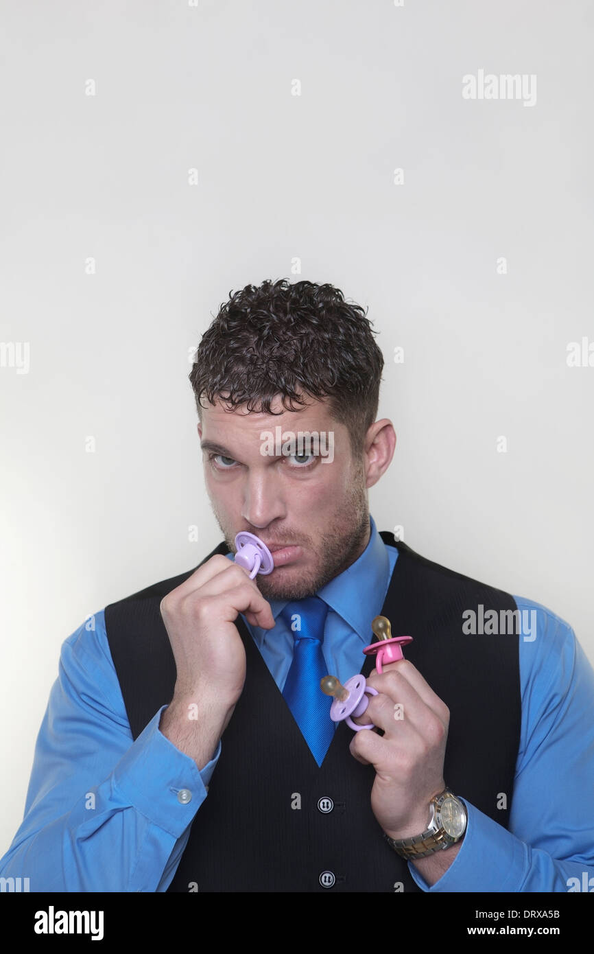 handsome man with a baby dummy in his mouth looking silly Stock Photo
