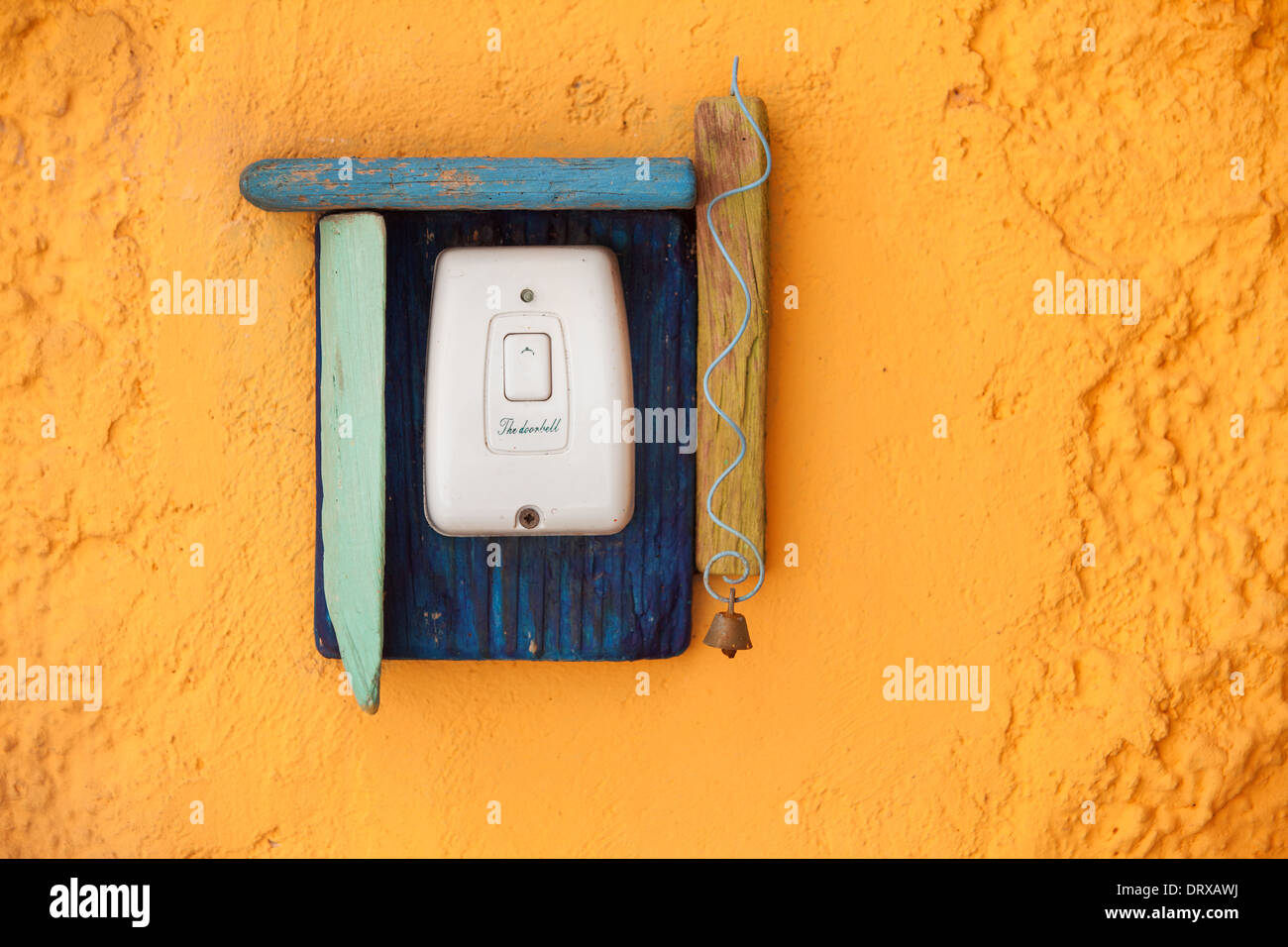 The doorbell button with wooden decoration on the old yellow wall. Stock Photo