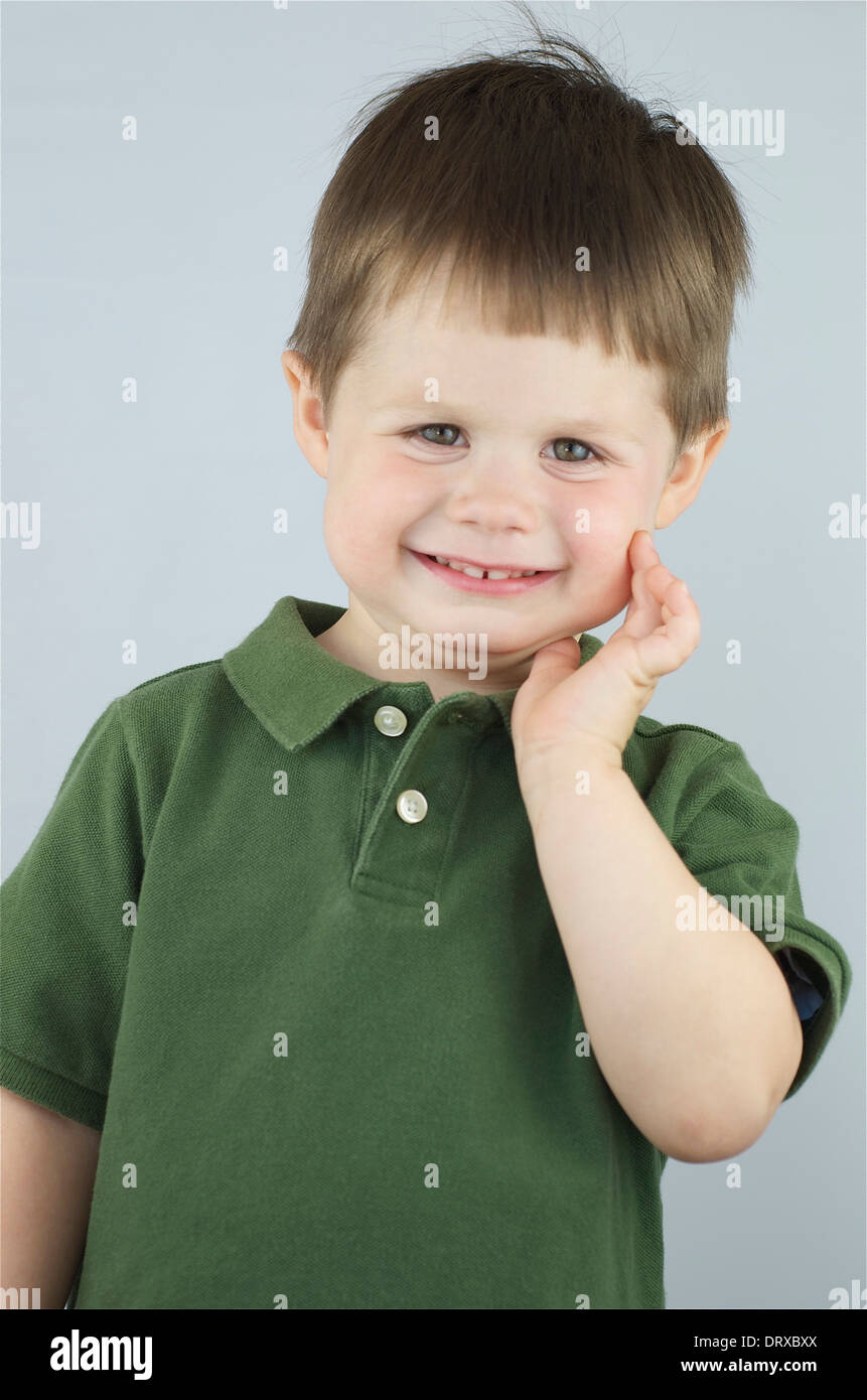 Little boy with hand by his face and cute smile Stock Photo