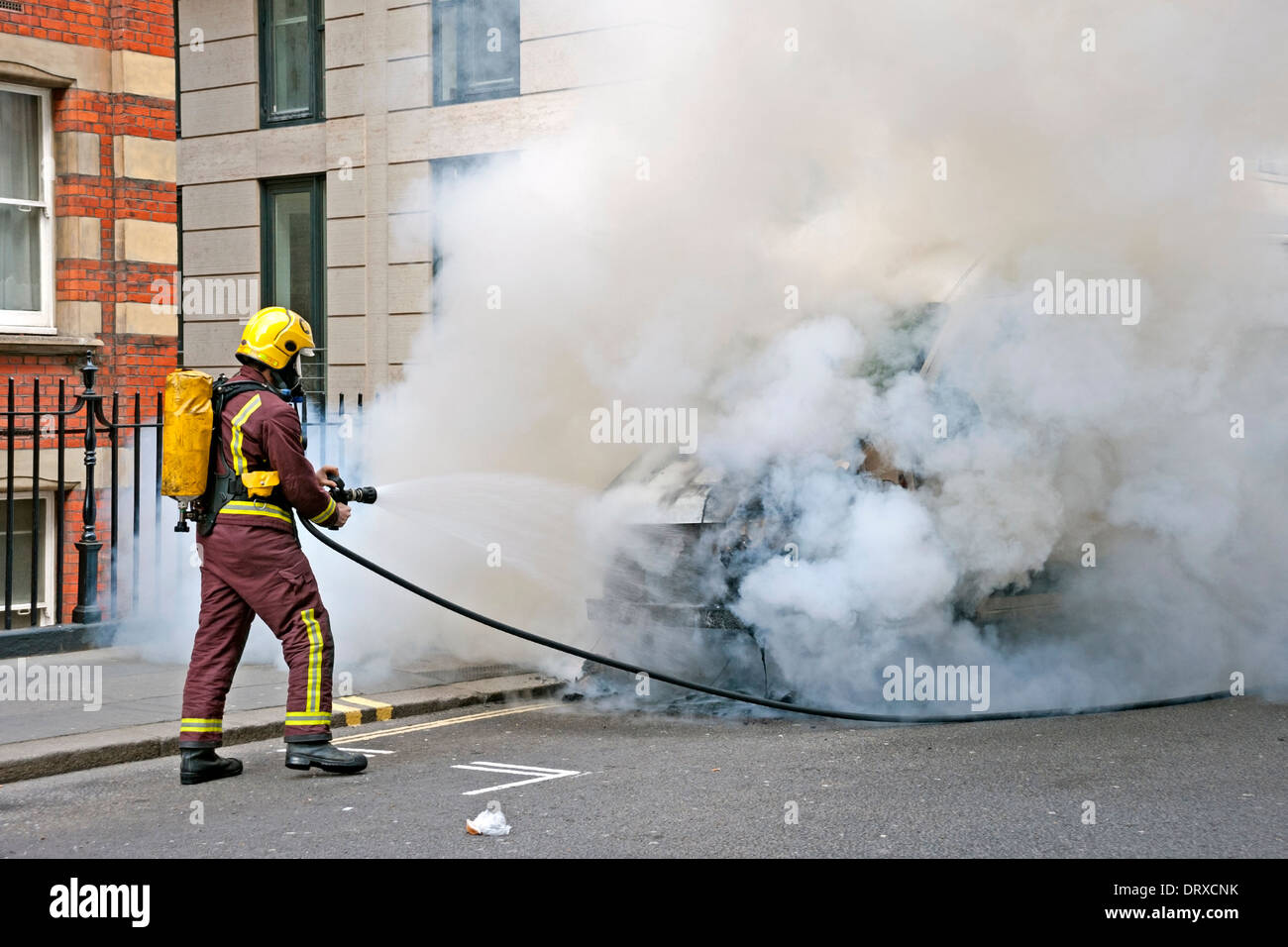 Fireman tackles a fire on a van in a London Street Stock Photo