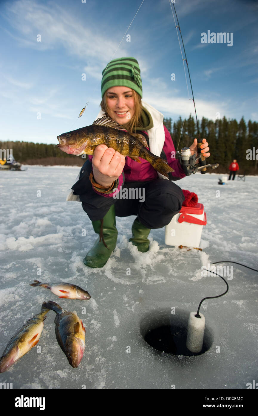 A young woman holds up a winter walleye she caught ice fishing Stock