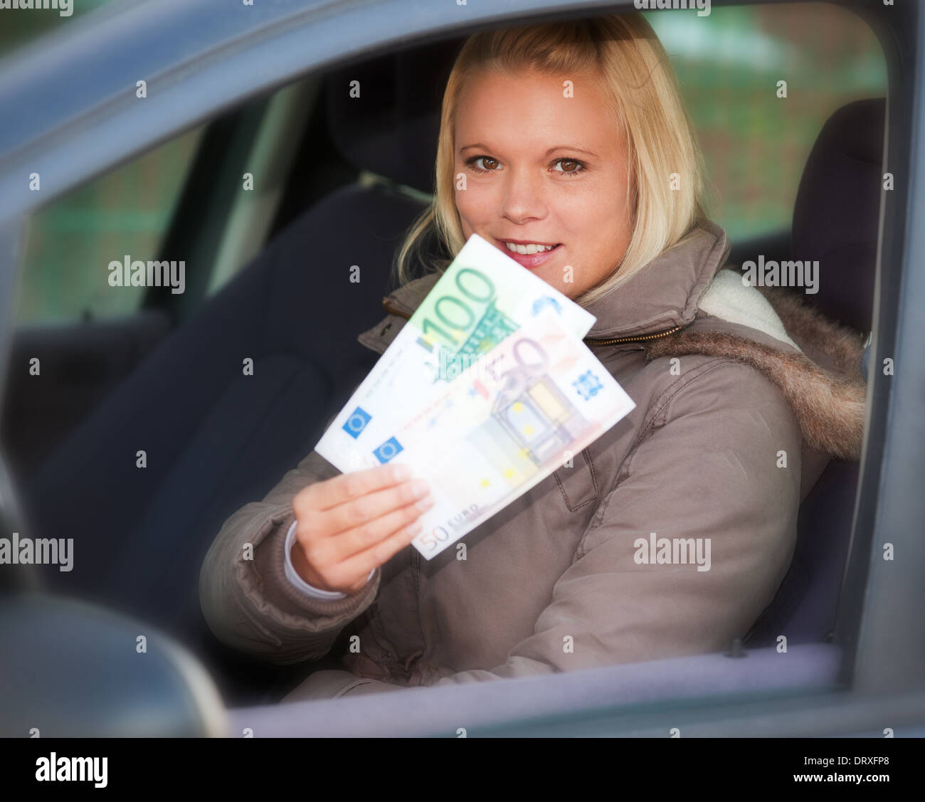 Young woman in her car holding 150 euro Stock Photo