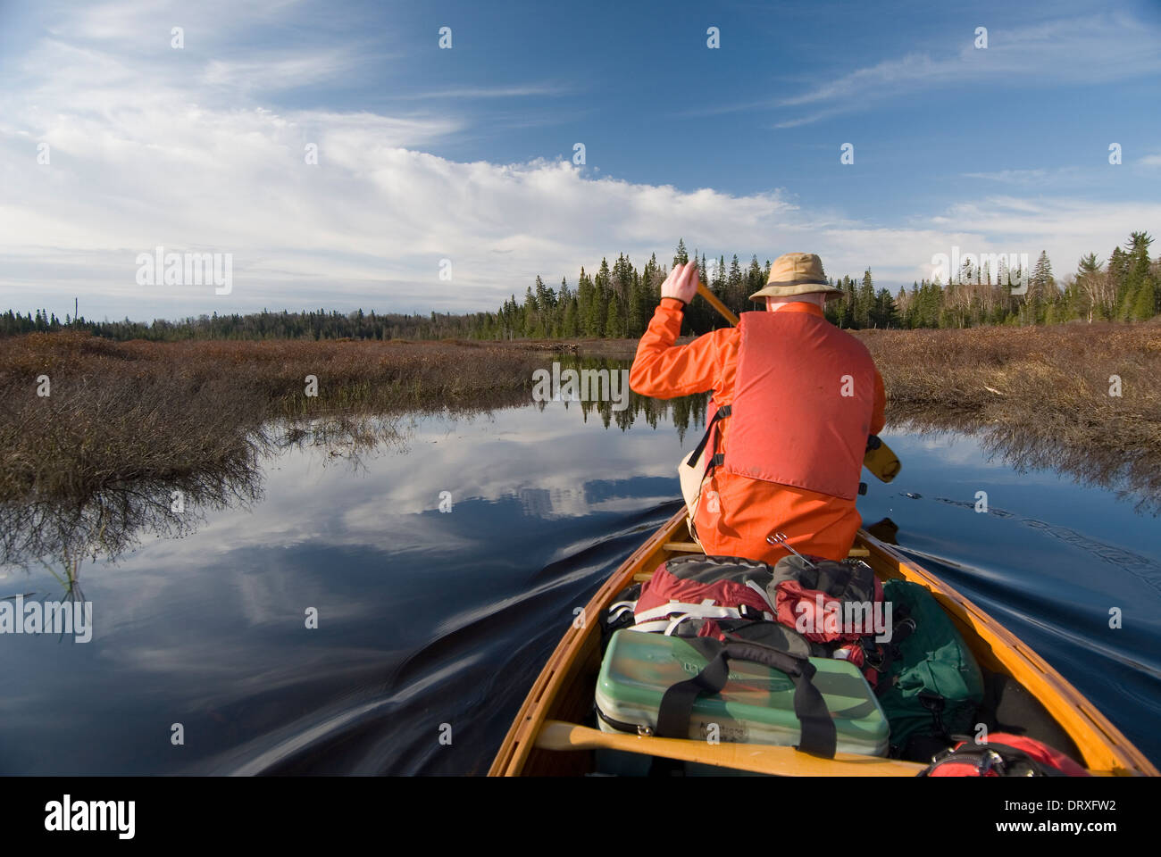 A man paddling a canoe in a calm lake in Northern Ontario Stock Photo
