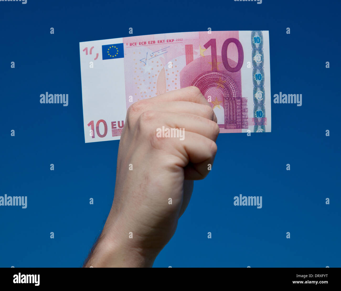 Hand holding 10 euro note in front of bright blue sky. Stock Photo