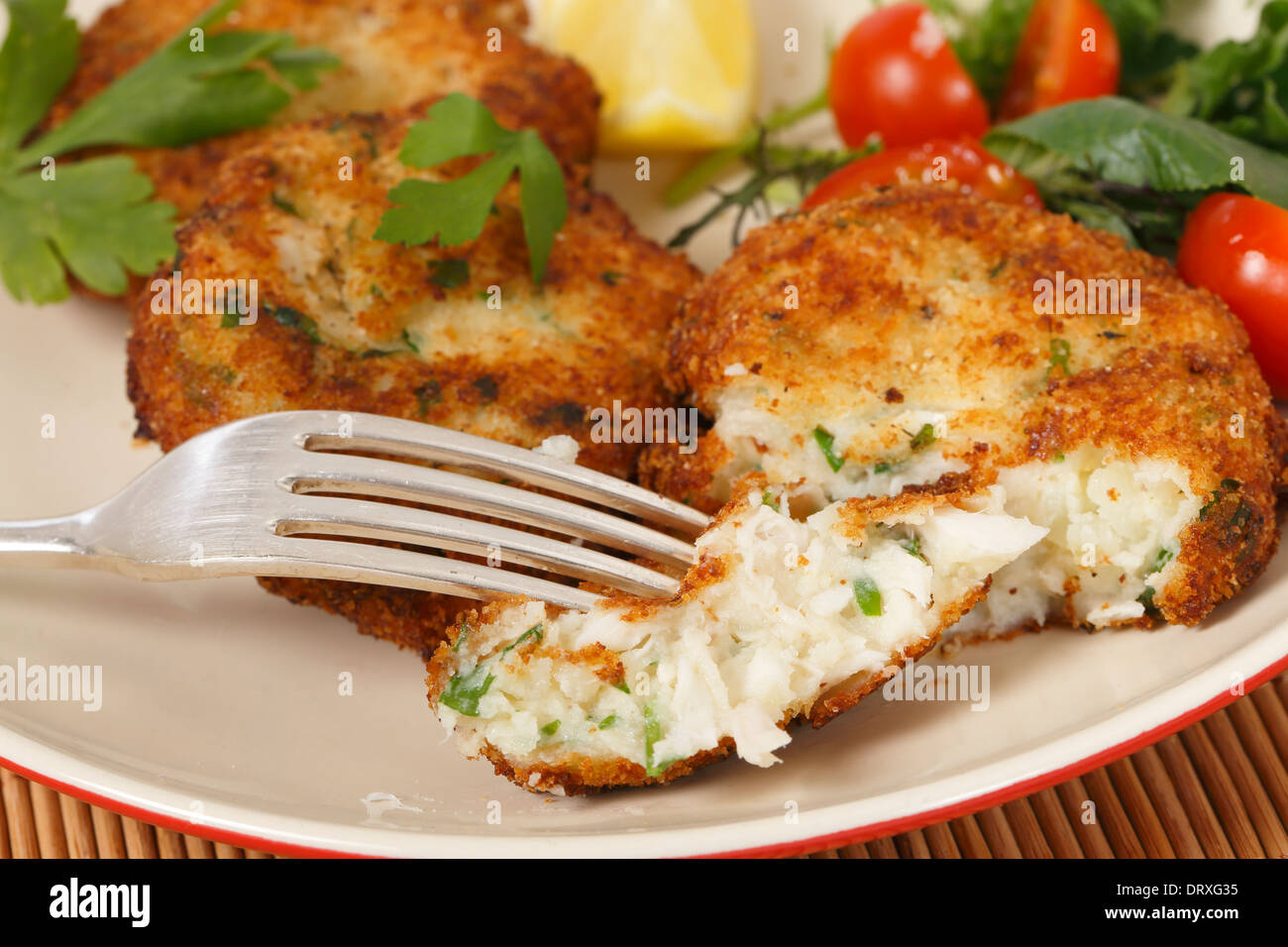 Easy to make fishcakes, with steamed fish crumbled into mashed potato and parsley mix,  served with a salad Stock Photo