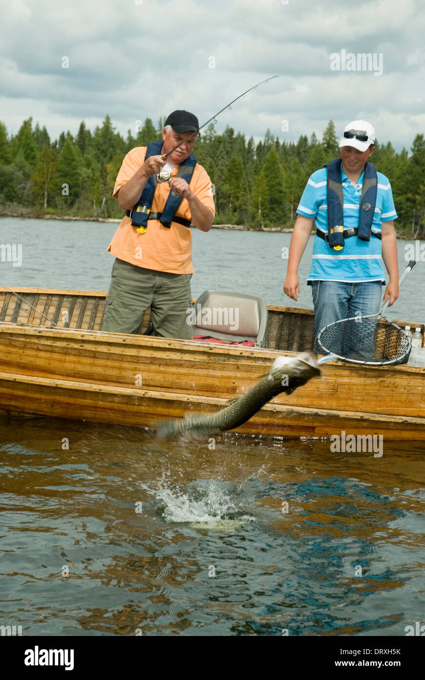 Father and son anglers landing a huge northern pike from their boat on a lake in Northern Ontario, Canada Stock Photo