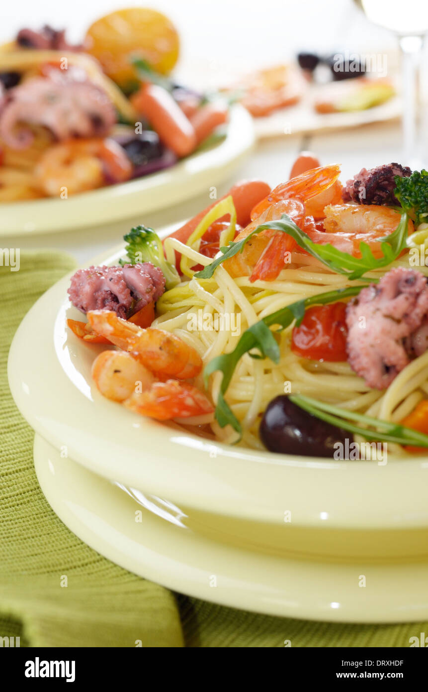 Seafood spaghetti pasta dish with octopus, shrimps, cherry tomatoes and olives Stock Photo