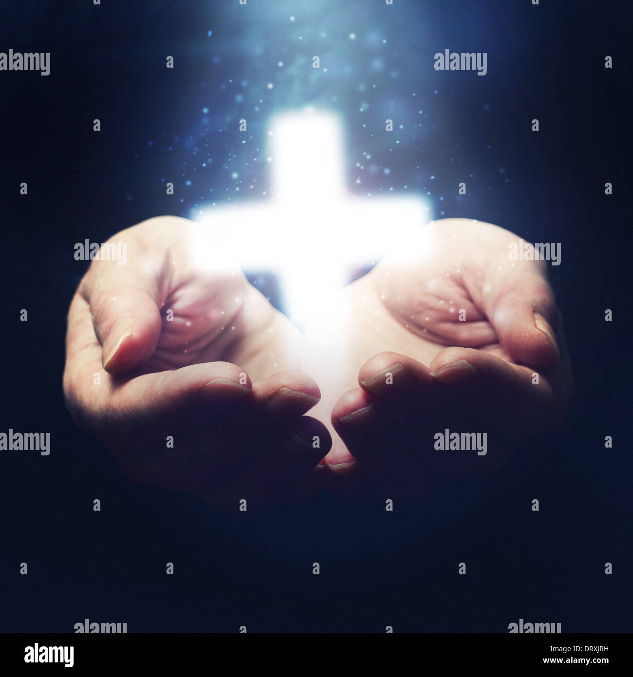 Open hands holding cross, symbol of Christian faith Stock Photo