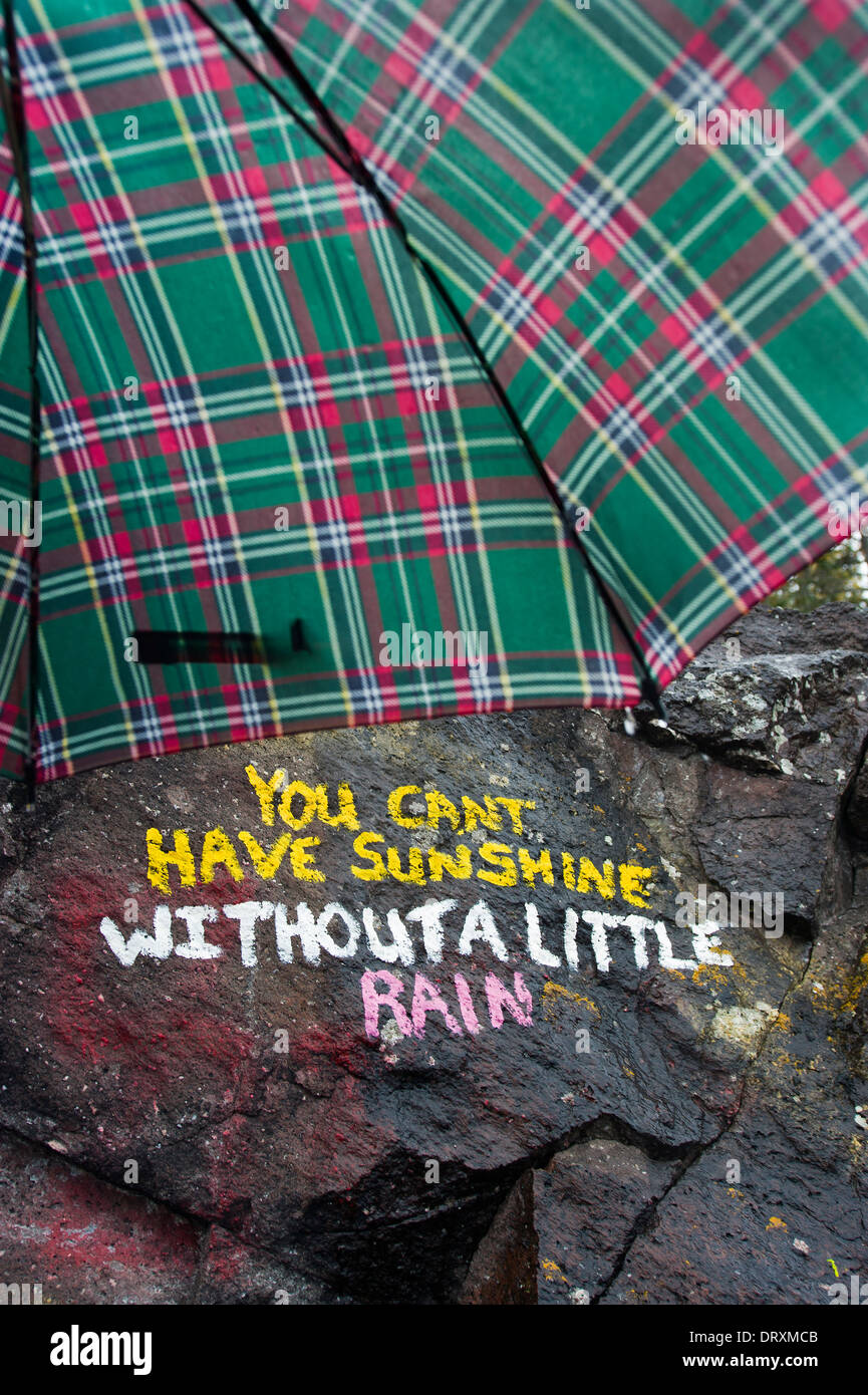 Umbrella over a hand written sign on a rock. Stock Photo