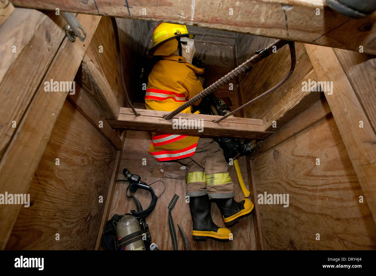 High school fire academy student crawls through obstacle-filled house looking for trapped 'occupants' during training exercise Stock Photo