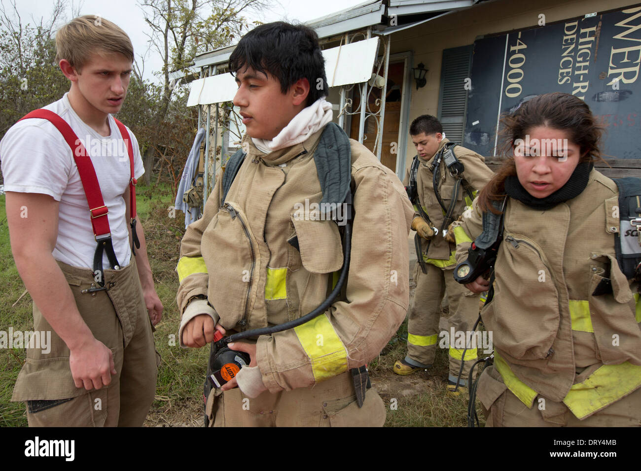 Students from high school fire training class unload gear after practicing fire fighting skills in abandoned house Stock Photo