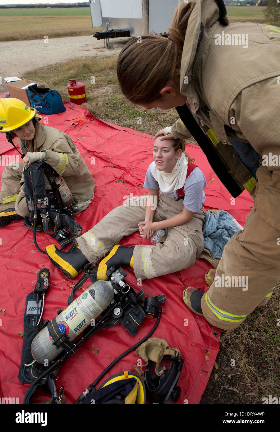 Students from high school fire training class rest after practicing fire fighting skills in heavy gear. Stock Photo