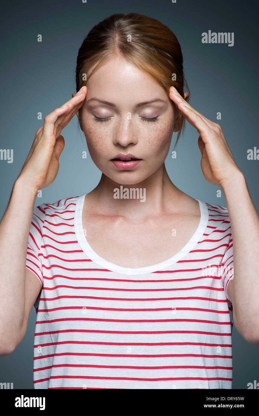 Young woman pressing sides of head Stock Photo