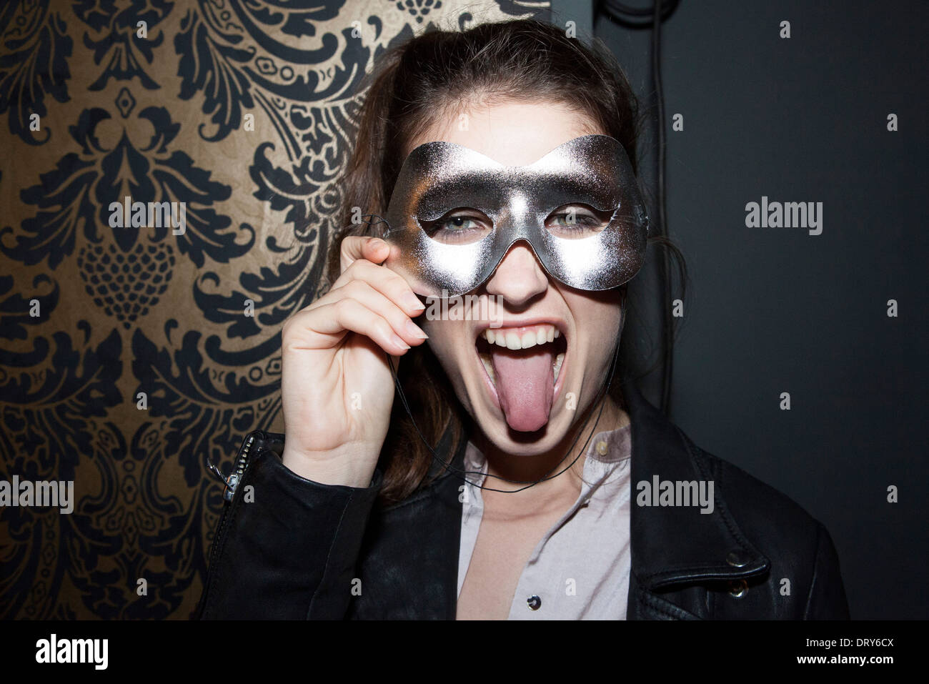 Woman wearing party mask, sticking out tongue, portrait Stock Photo