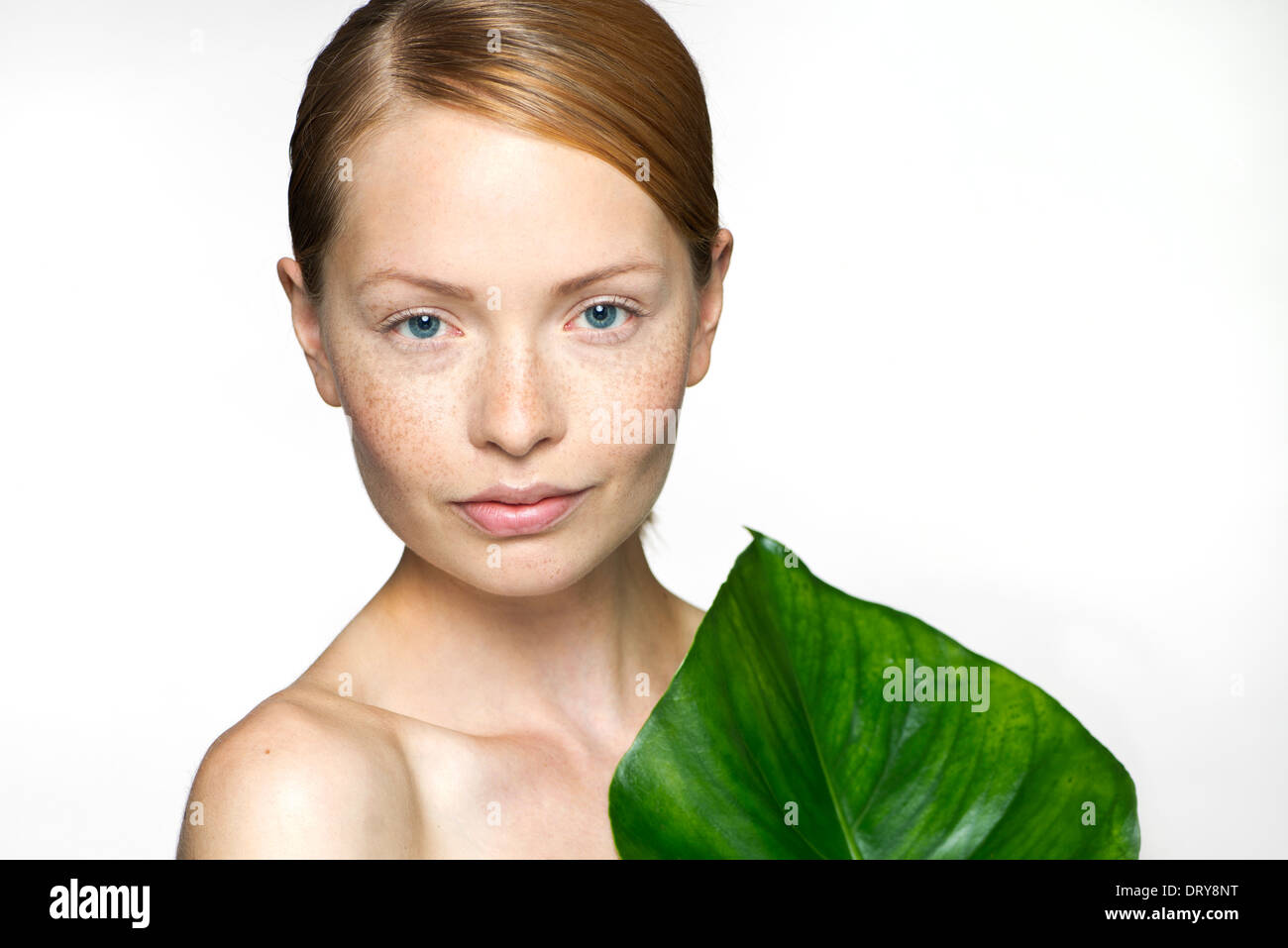 Young woman with tropical plant leaf, portrait Stock Photo